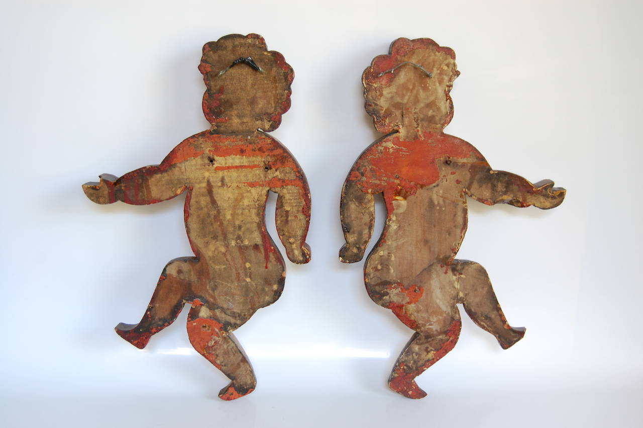 Pair of matching left and right facing original putti figures purported to be from a very early merry go round in New Orleans. These have been in our possession for more than 50 years. Carved of solid wood they are in very good condition and measure