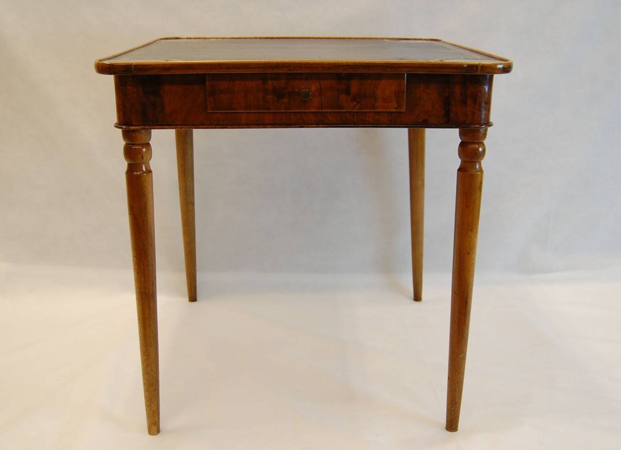 Early 19th century walnut card table with gold-embossed black leather top and single drawer. Turned legs are glued into the body of the table, very sturdy and well built. Leather top has minor marks; the gold embossing is in very good condition. The