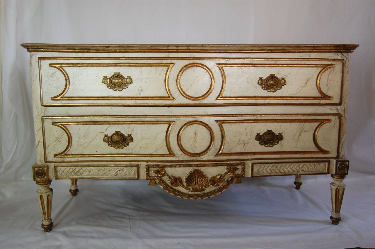 Cream paint and parcel gilt commode, late-18th century to early-19th century. The cabinet is tight and the drawers work well, in original painted finish. The drawers have sliding half trays for smaller linens, and are lined in a cotton chintz fabric.