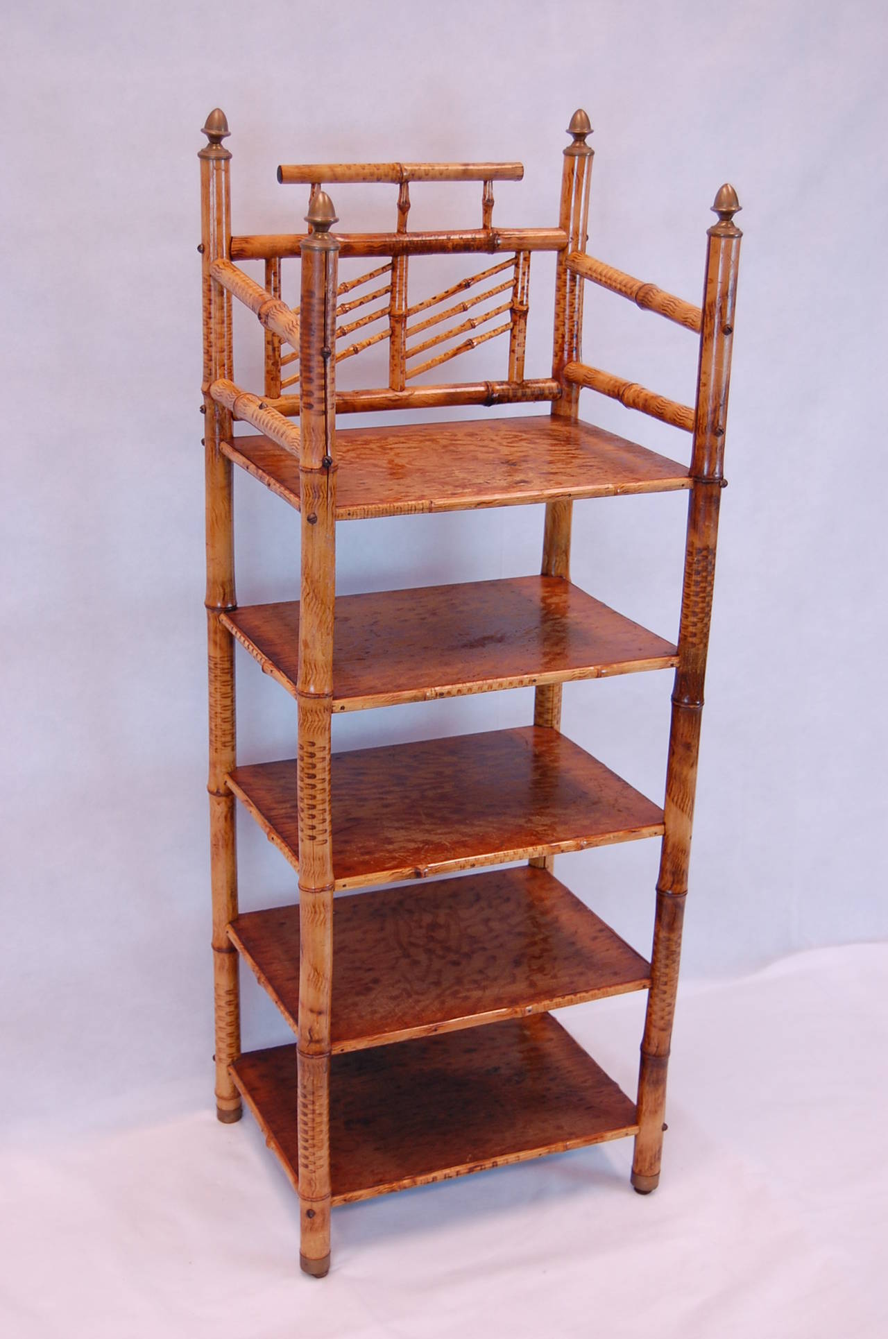 Faux finished bamboo stand with 5 shelves and brass finials atop each leg as well as brass caps at the base of each leg. Reasonably tight frame.
