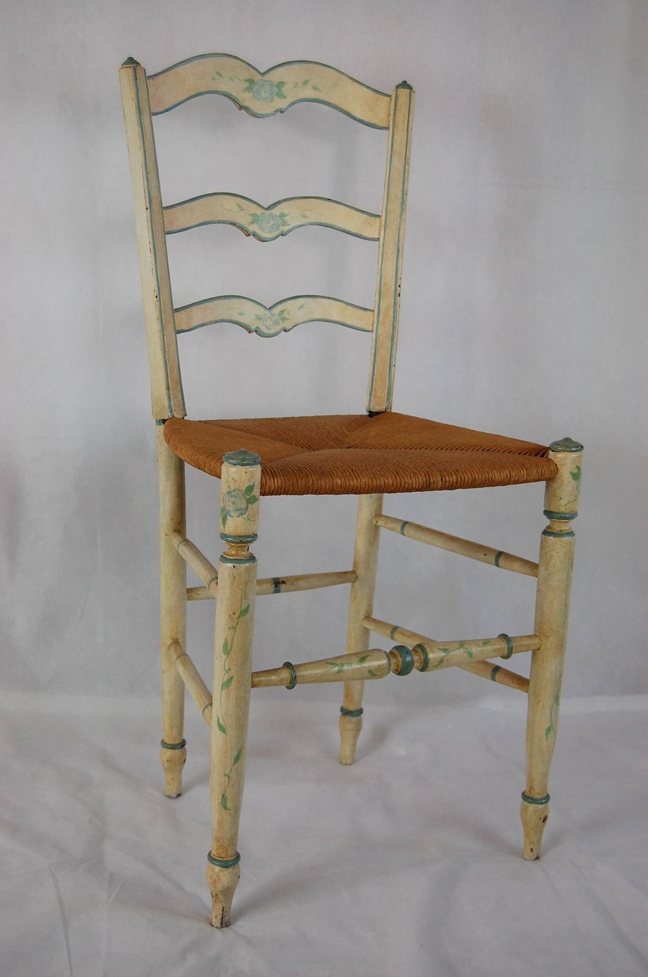 Petite French-style side chair in white paint finish with floral decorations and rush seat. In excellent condition with an age relative patina. The frame is tight and the seat was replaced a few years ago. Seat: 15.5