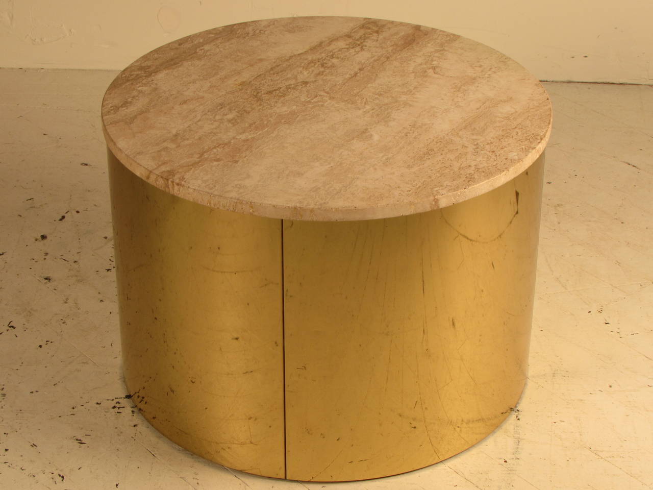 A drum table in a mirror polished finish with a thick travertine top. Signed C. Jere. The brass glows with a warm golden tone. Dimensions of this piece could work as either a side table or small cocktail table. 

Brass is in good condition with