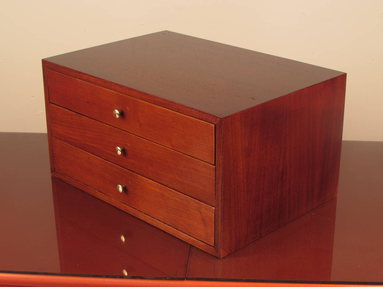 Dapper 3 drawer dresser box or jewelry box in the style of Paul McCobb. The wood appears to be teak and drawer pulls are polished brass. This piece has been fully restored.