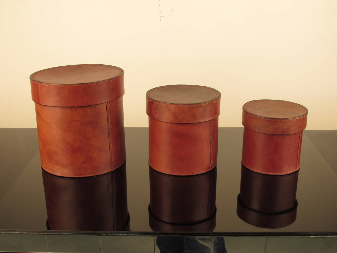 Handsome set of three leather lidded vessels or canisters. Leather is heavy, rich and buttery with a perfectly broken in look. Substantial overstitching gives these pieces added texture and dimension. Incredible quality and