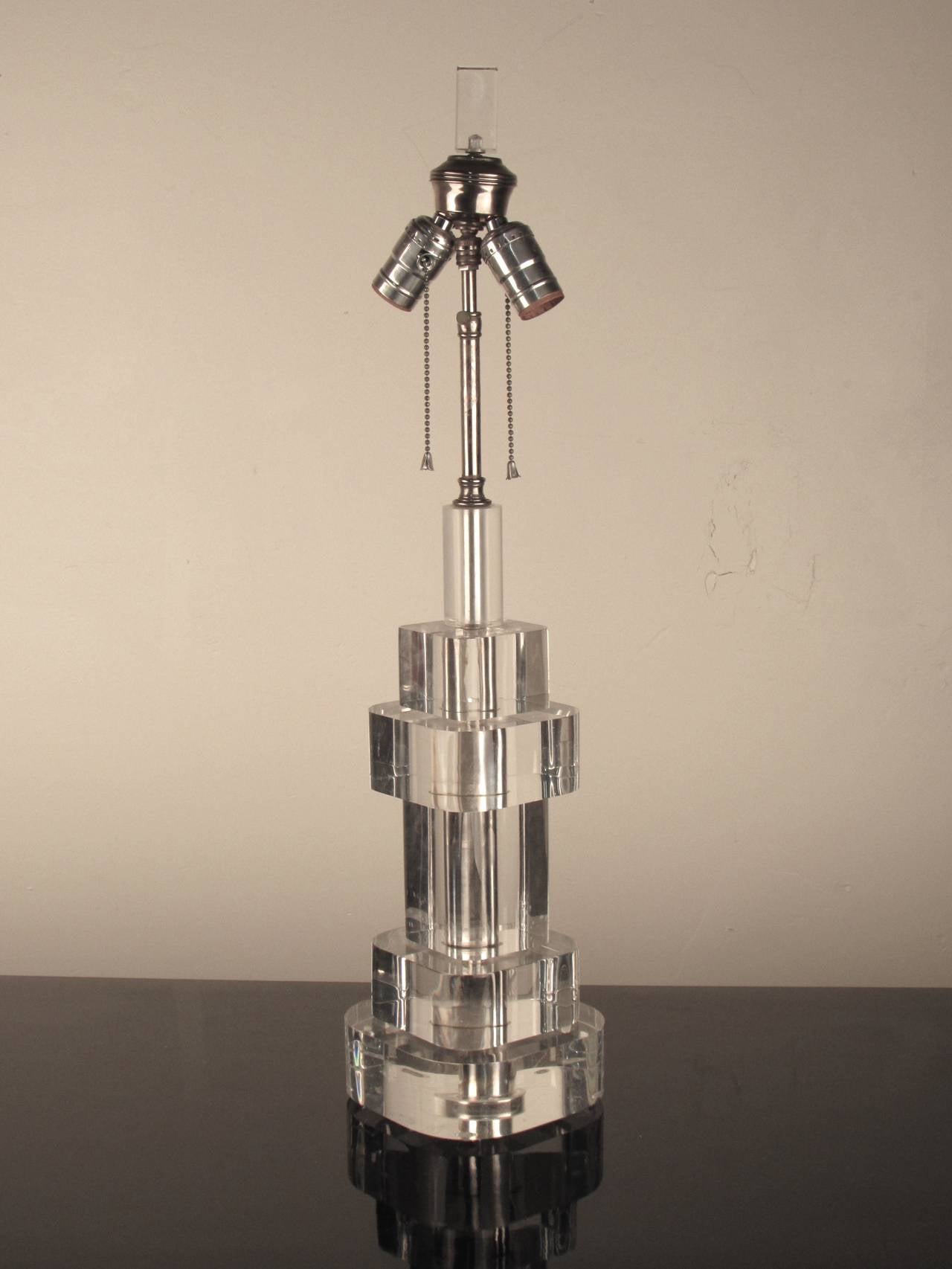 Striking stacked lucite table lamp with original lucite finial and chrome details in the manner of Karl Springer. Lucite is thick and substantial and in excellent condition. Lamp has been rewired and uses two standard socket bulbs. 

Dimensions: