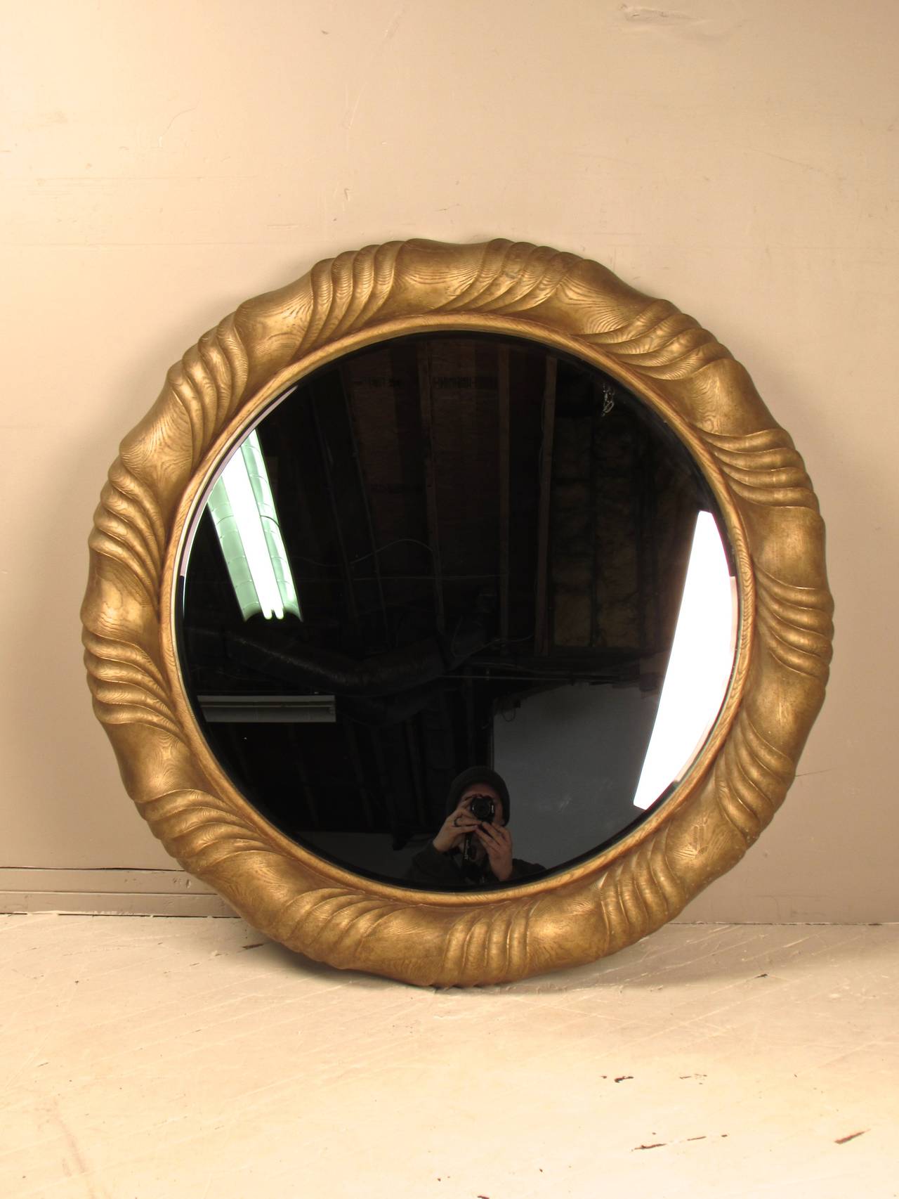 Monumental, nearly 4 feet in diameter, round wall mirror. with beveled edge. Constructed of thick cast and sculpted resin which has a woodgrain texture and gilded finish. The wood grain is so convincing that it truly looks like wood, even at close