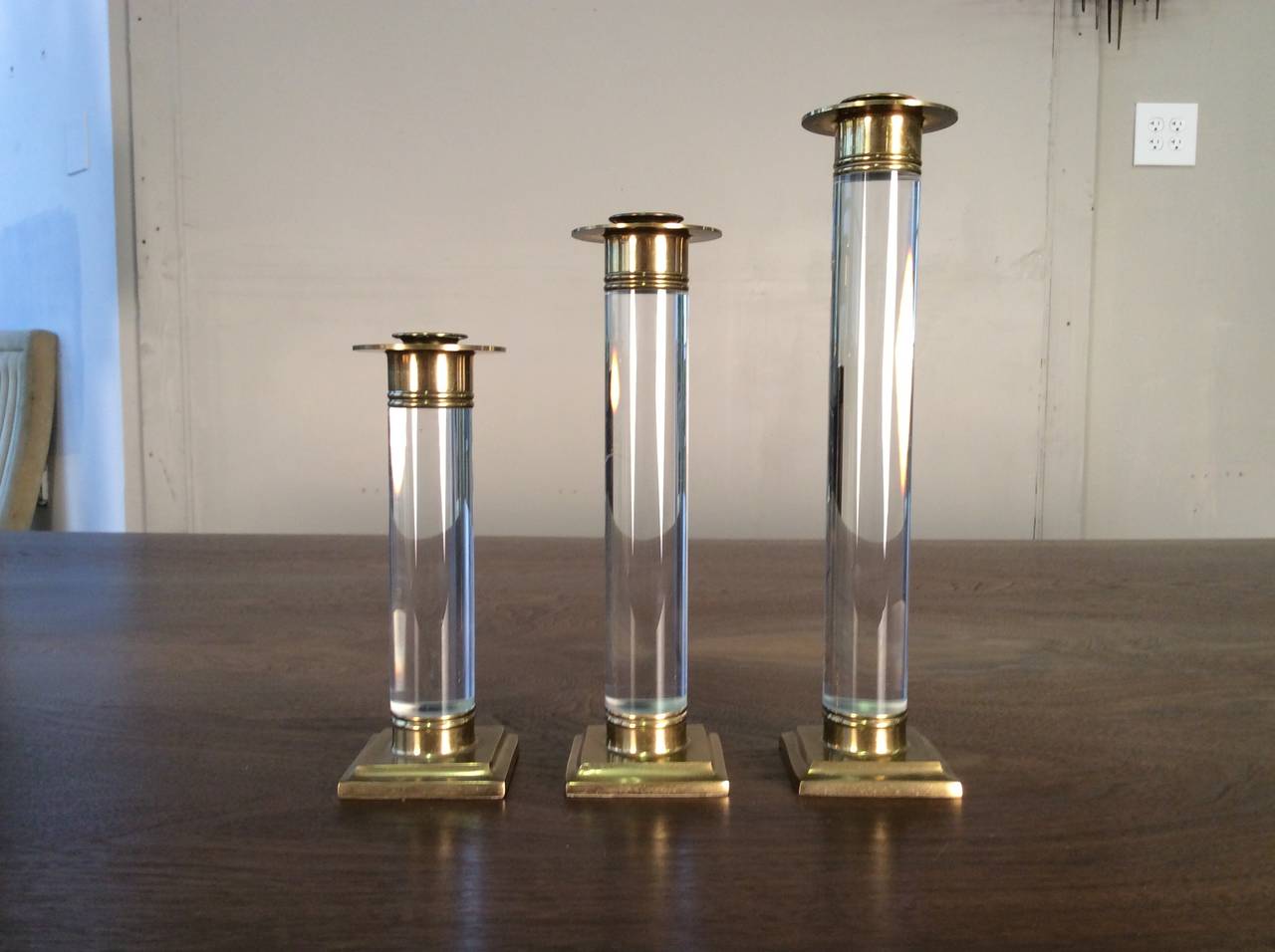 A Trio of Lucite and Brass Candlestick Holders in the style of Karl Springer. This set is in fantastic condition with beautiful patina. Lucite shows very well with only a few light surface scratched.

Dimensions:

7 1/2