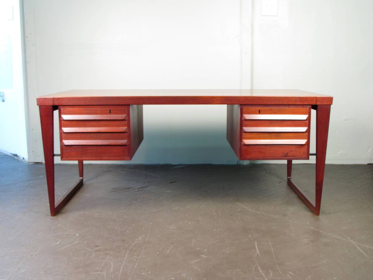 Large handsome Danish modern executive desk on sled base by Kai Kristiansen, circa 1960. The teak construction is substantial and sturdy. This piece in excellent condition with normal wear for age and use. Comes with one key that locks the front