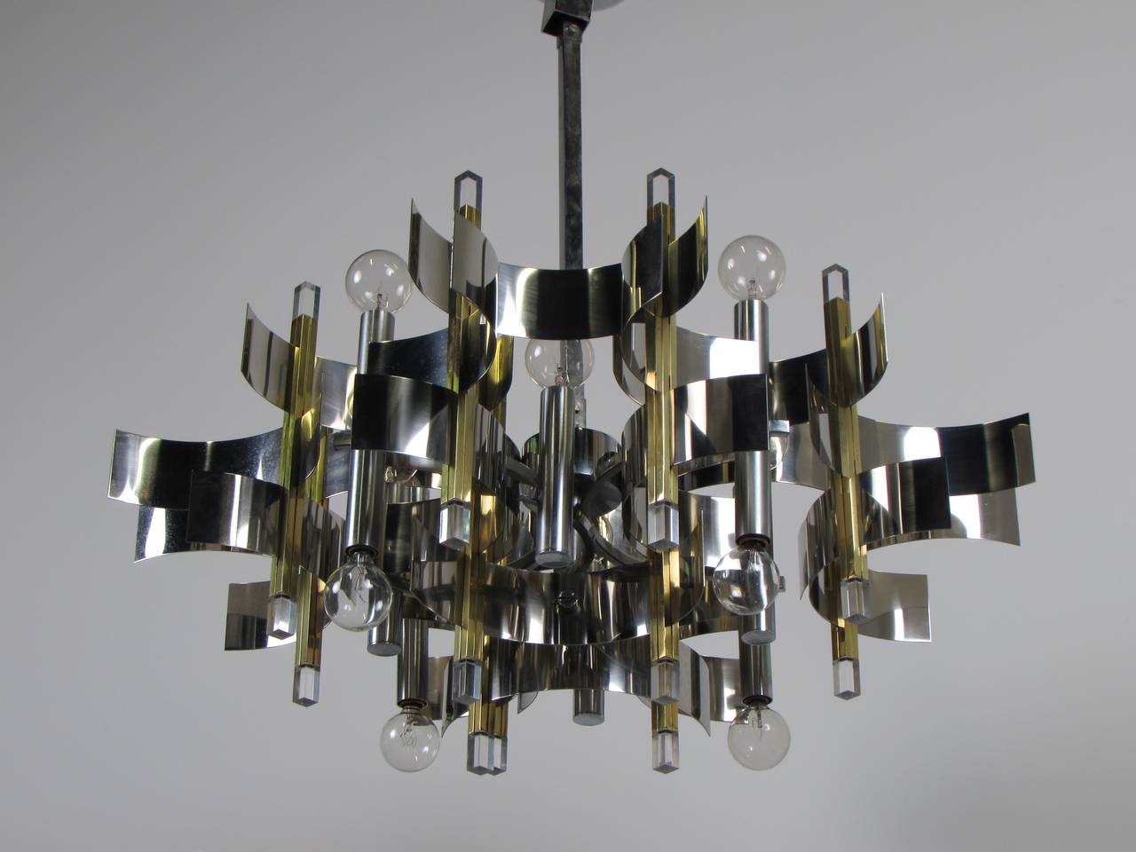 Sculptural brass, chrome and Lucite chandelier by Gaetano Sciolari, signed 1970s. Composed of demilune strips of chrome woven and stacked around brass bars with Lucite tips. Condition is excellent. Scholar sticker is present.

We offer free