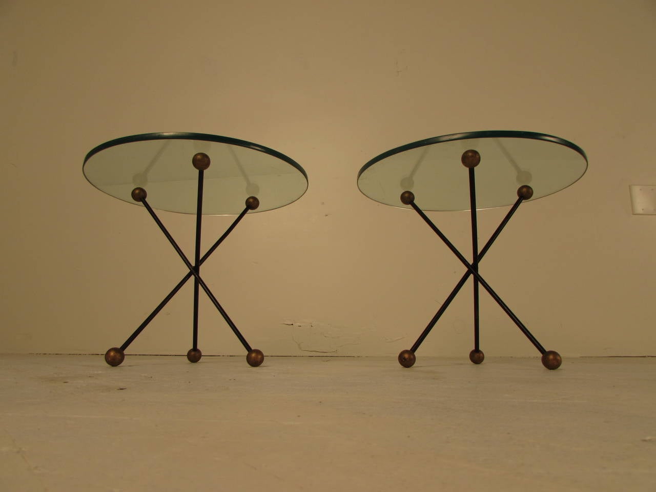 A vintage pair of French end or side tables in the shape of jacks. Thick glass tops and enameled steel bases with gilded wood ball details. Lovely petite scale. Maker unknown, pieces are unsigned.