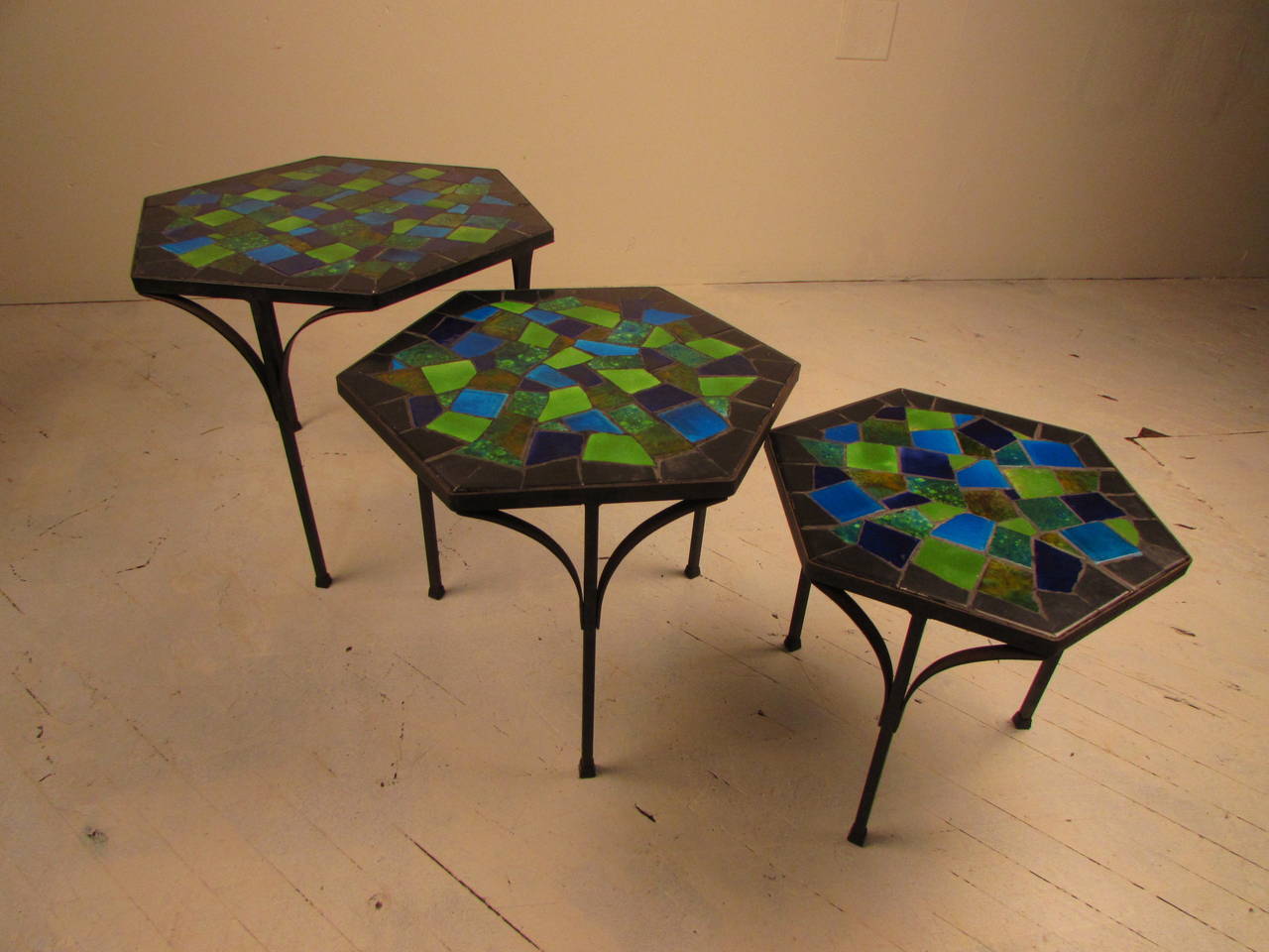 Set of three hexagonal nesting tables by mosaic artist Jon Matin. Tables have inset multicolored mosaic tiles set into an iron base. Incredible, vibrant color and charming forms. Overall very good vintage condition with some minor grout losses.