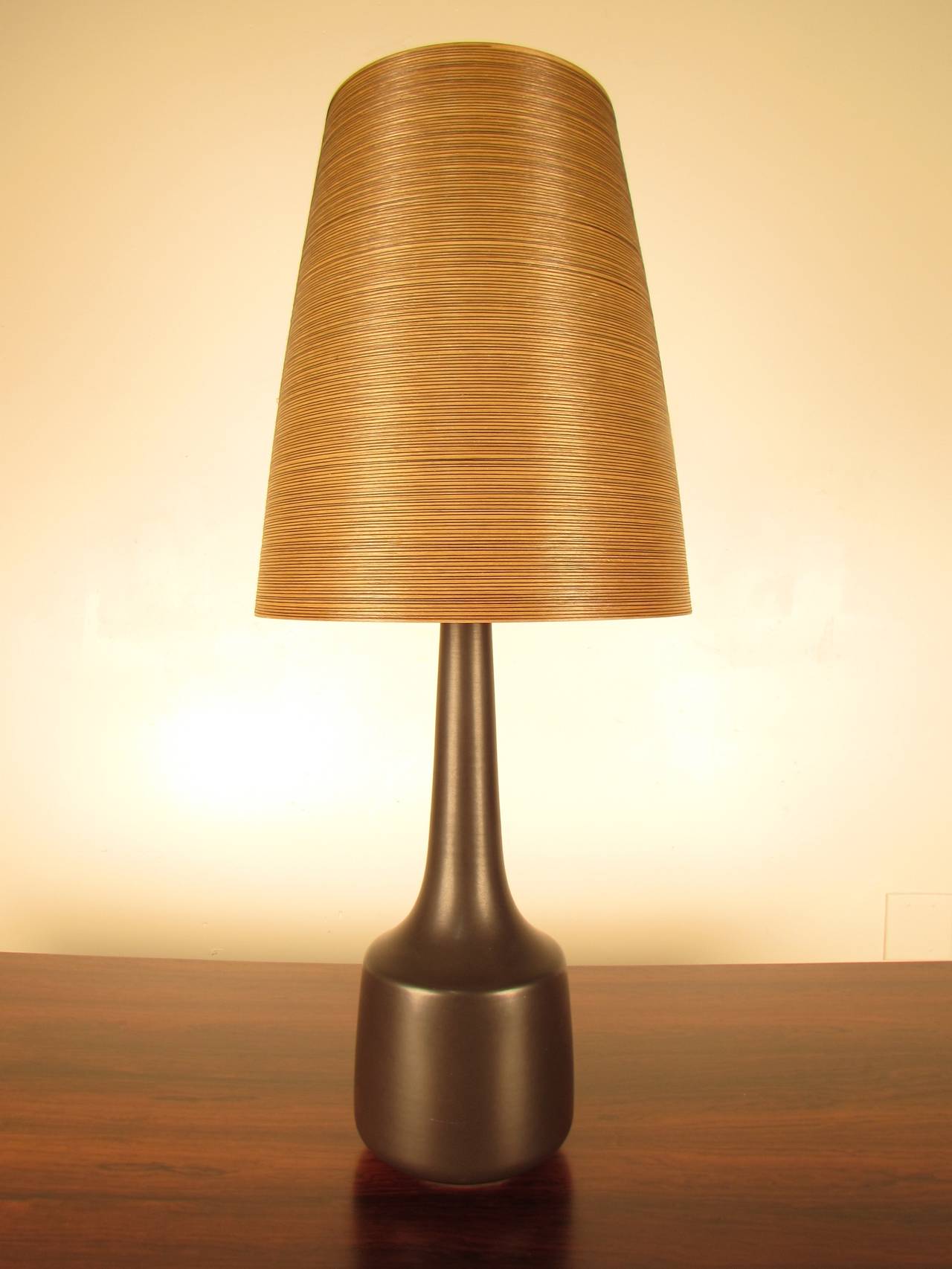 Tall, slender ceramic lamp by Lotte Bostlund (Canada). Timeless gunmetal glaze is wonderfully buttery and tactile; a striking juxtaposition to the ribbed resin shade, which is original to the piece. Lovely original finial has warm, rich