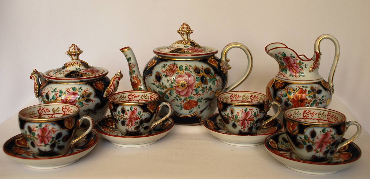 Coral decorated gold, pink and orange Imari tea set.  Continental gilt porcelain coral decorated Imari tea set with lidded teapot, creamer, lidded sugar and four teacups and saucers. Europe, 19th century. 