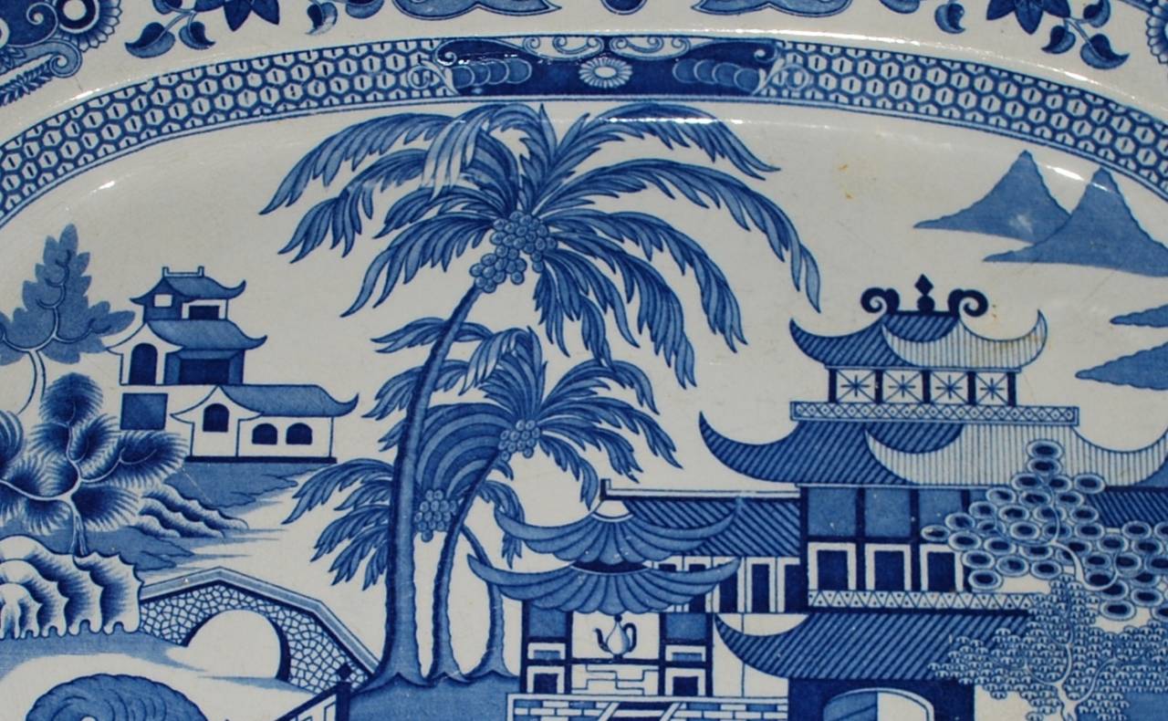 Large blue and white chinoiserie platter. Oversize blue and white English antique platter/serving dish from the Chinoiserie period of the 1820's-30's with oriental figures in landscape with palms and pagodas on a lake with boaters. England, 19th