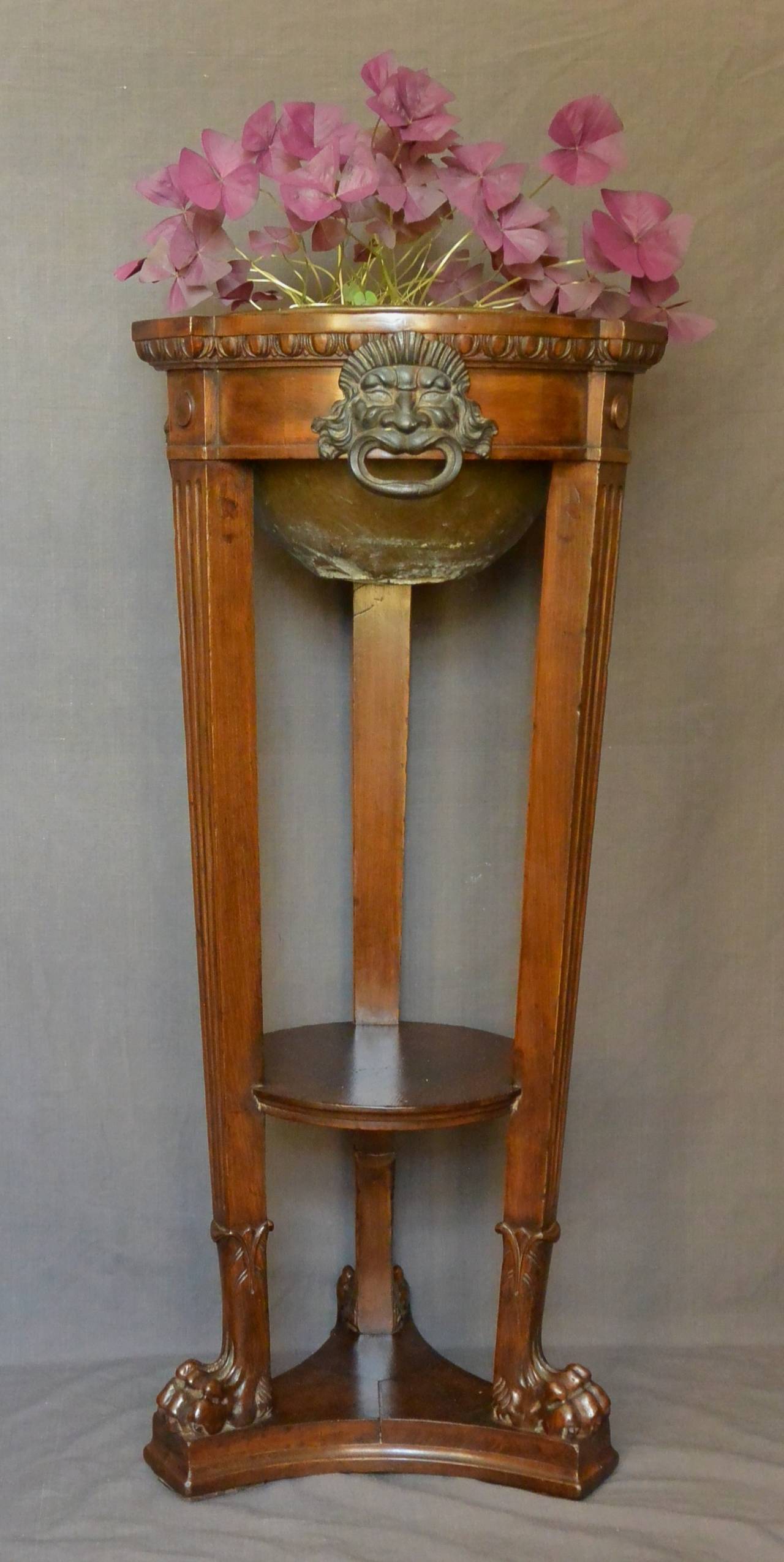 Italian neoclassical athenienne planter. Walnut jardinière with cast-iron Etruscan mask-form handles, tapering fluted legs ending in paw feet on in-curving shaped plinth with copper planter insert.
Dimension: 37.5