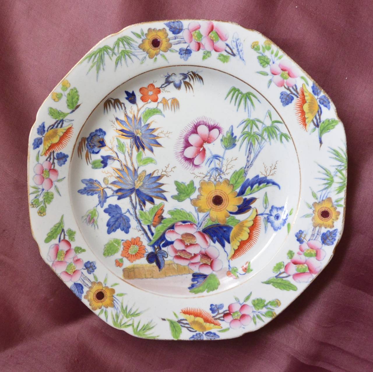 Britannicus Dresden China ironstone octagonal plate in blue and enriched with gilt and brightly coloured enamels with flowering plants and bamboo in the oriental taste, c.1820. Underglaze blue stamped. 
Dimension: 10
