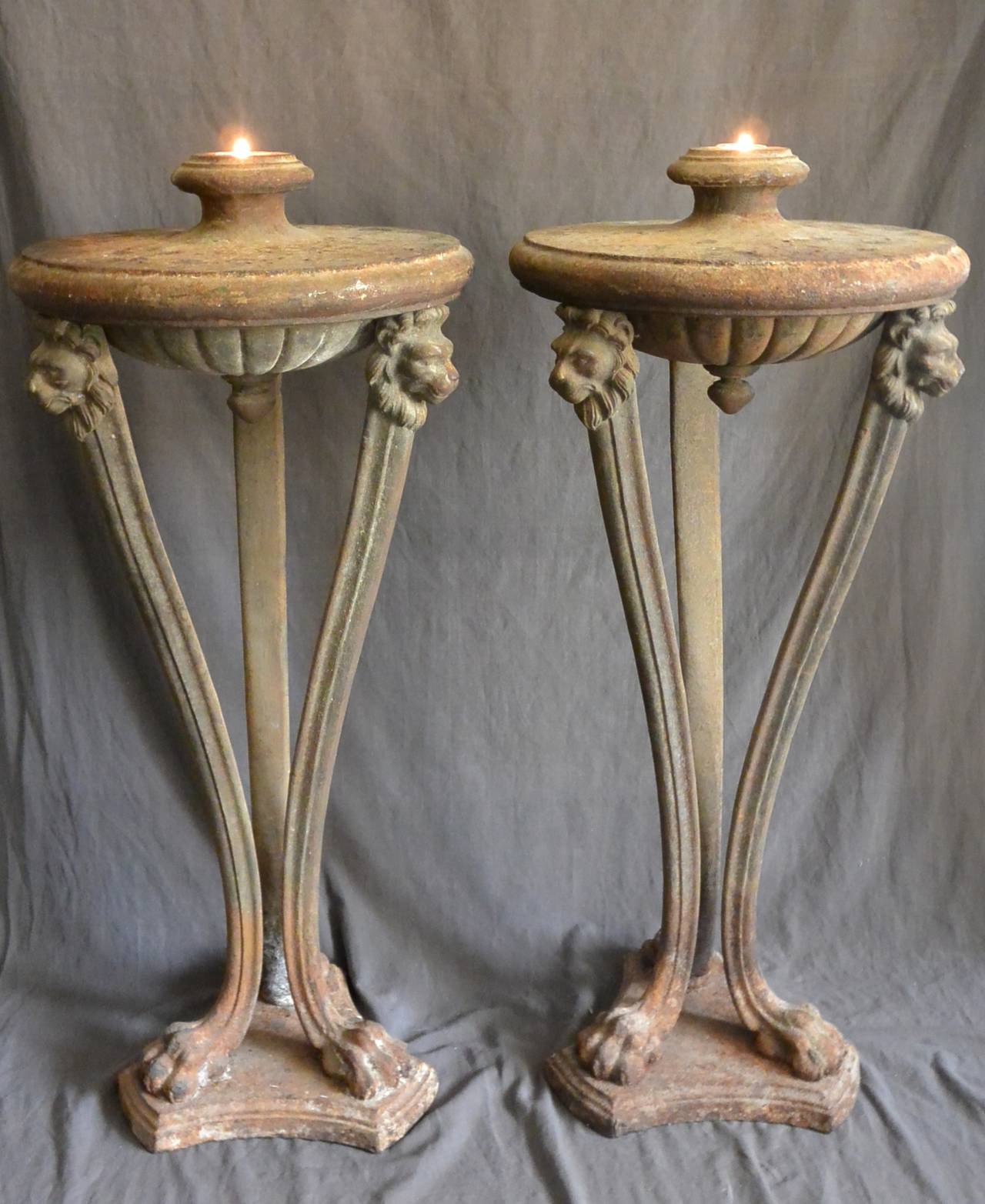 Pair large Italian cast iron atheniennes.  Tripod form oil lamps after the antique with urn shaped lamp raised on lion-head masks terminating in lion monopedia on in-curving shaped plinth.  Italy, 19th century. 
Dimension: 19