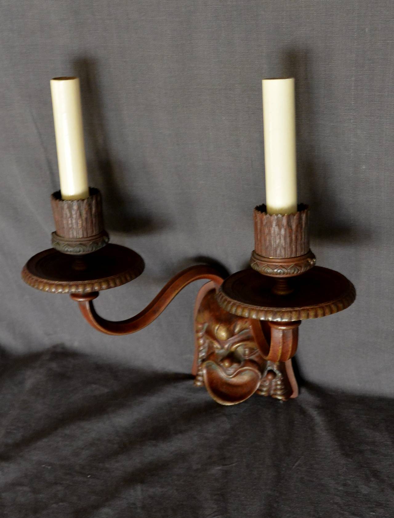Aplique de máscara etrusca. Máscara de bronce patinado de estilo etrusco que emite un par de brazos de vela neoclásicos. Recién electrificado. 
Dimensiones: 11,5