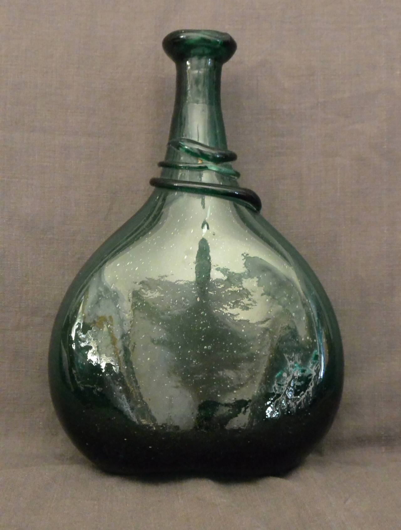 Antique green glass bottle. Flask is slightly molded to conform to horse's side.  Italy, 18th century. 
Dimension: 7.5