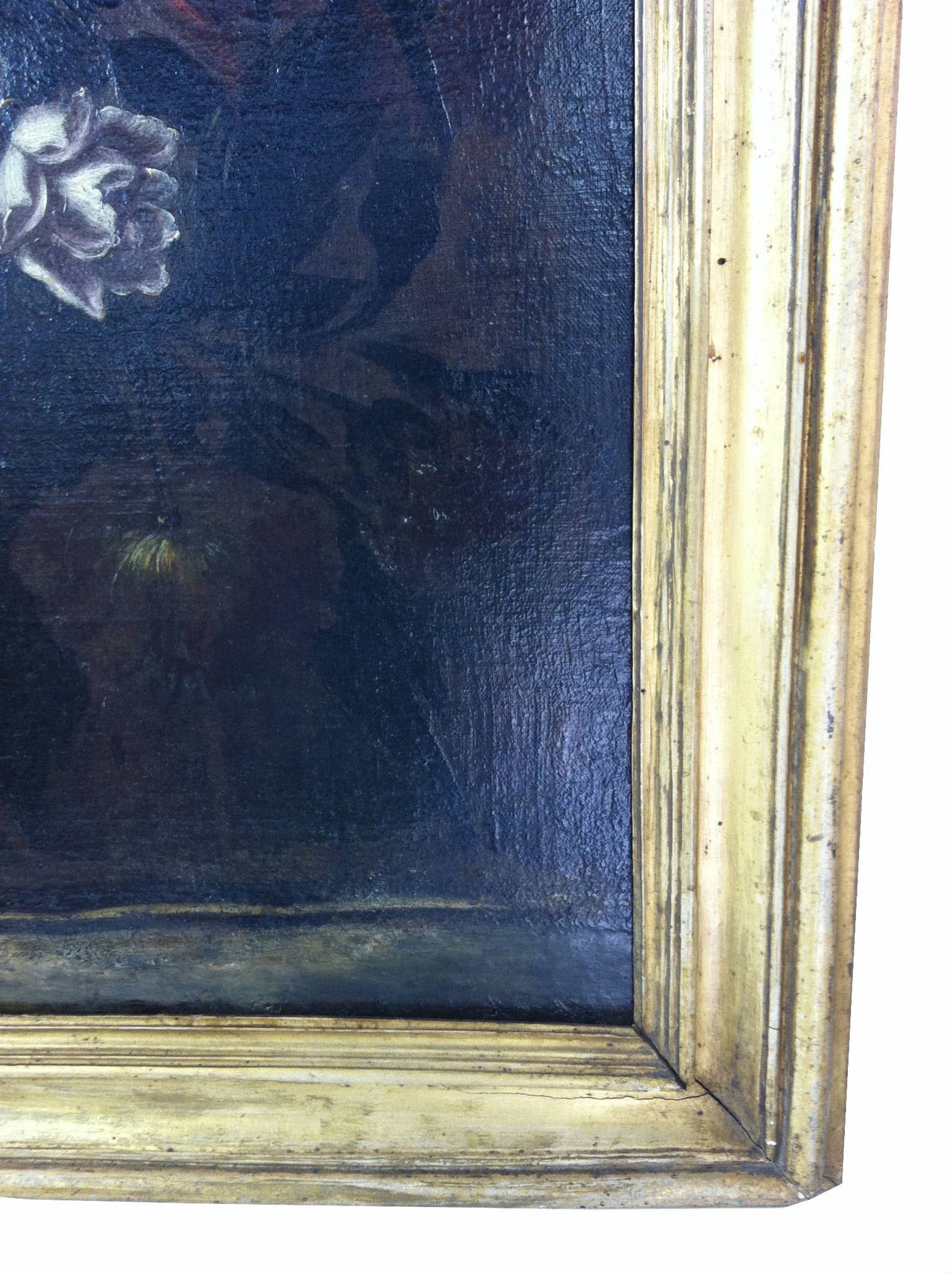 Oil on canvas with floral subject, done in a muted palette, with highlights of red orange, pale blue and grey.  Exquisite detail on flowers and vase. Original Gilt wood frame.
