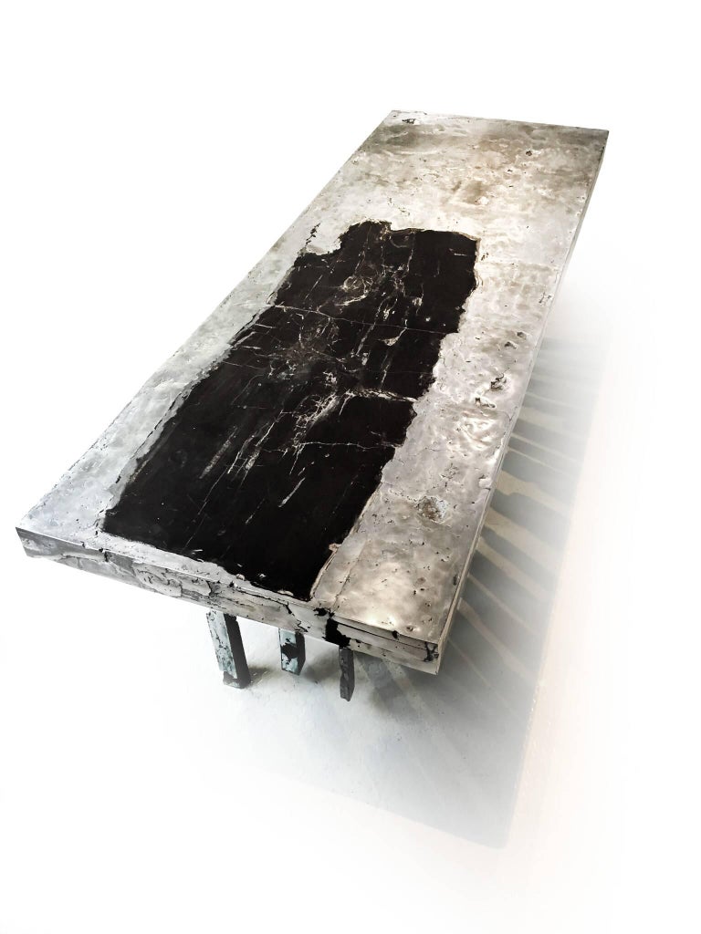 This one of a kind sculptural table is made with cast zinc and petrified wood. It weighs over 1000lbs and is a stunning masterwork of the designer John Brevard. This unique piece is made by placing coral in the mold and burning it out to open up