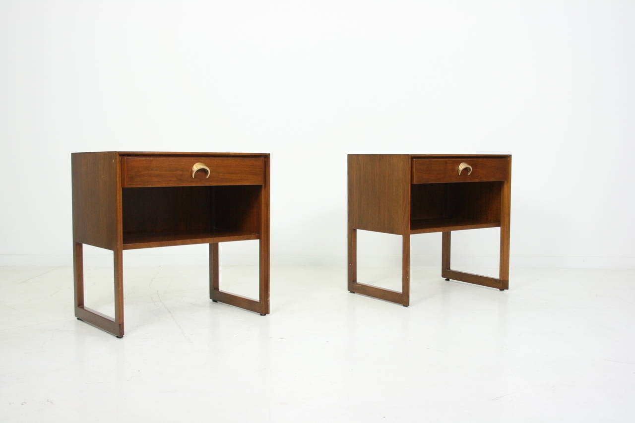 Jens Risom nightstands, by Jens Risom Design, Inc., walnut cases with exposed legs and floor stretchers, one-drawer with original brass crescent-shaped pulls, walnut top, back finished, signed in drawer.
