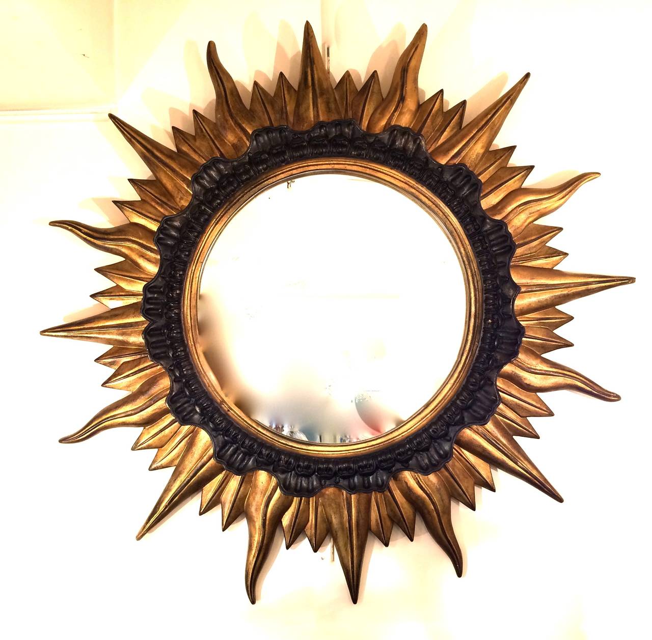 Big sunburst mirror in gilded and black laquer on resin.
France circa 1950.