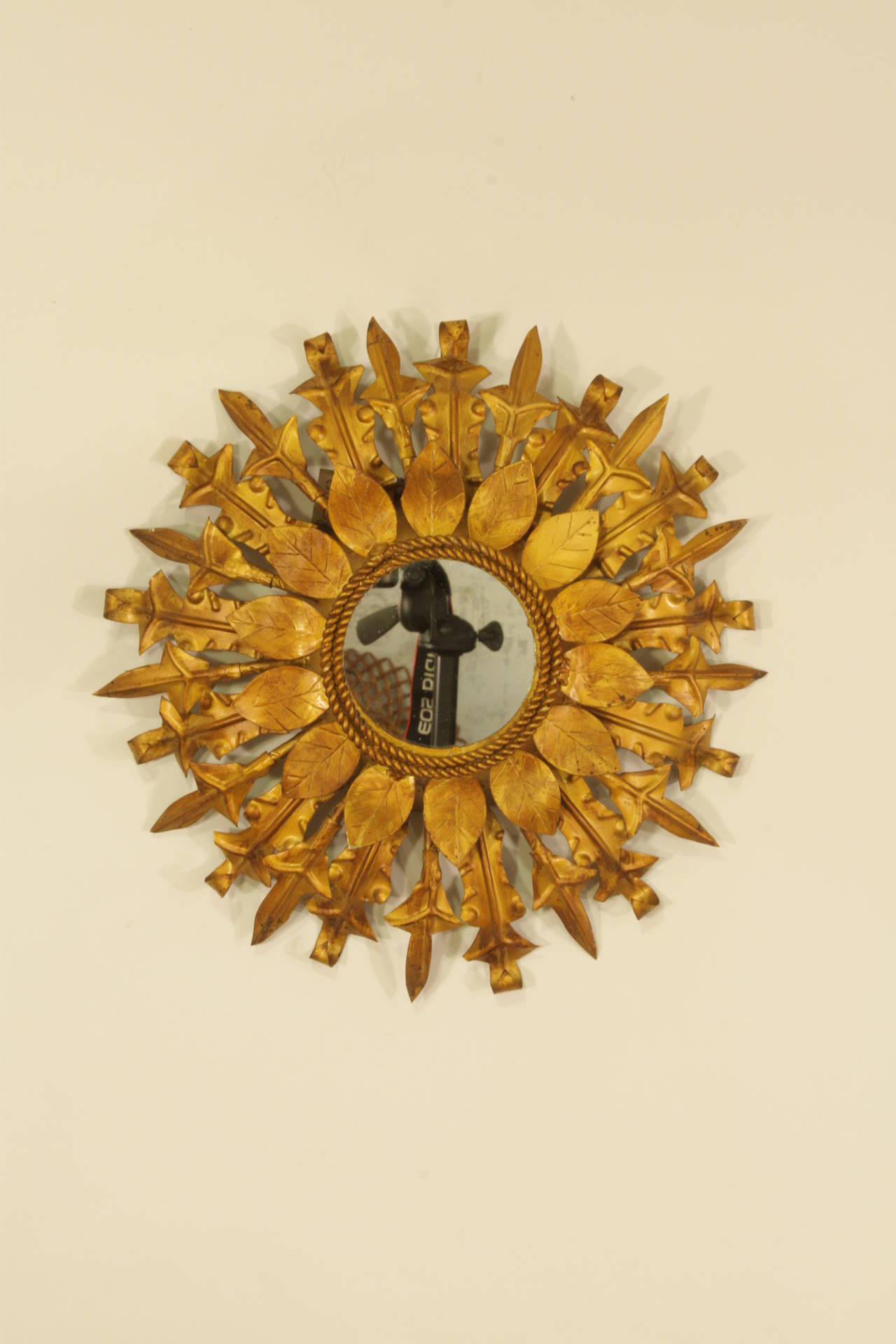 Lovely small flower burst or sunburst mirror: this piece has two lyers of concentric gilt leaves in different sizes. Lovely to pleace it alone but also creating a wall decoration with other mirrors in this manner.
Spain, 1960s.
Avaliable a huge