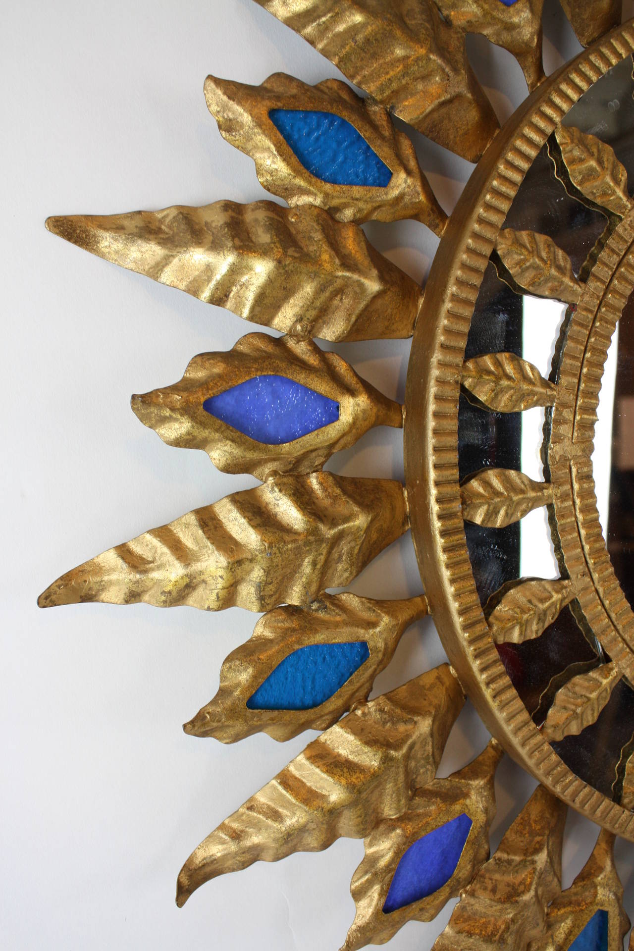 Spanish gilt iron sunburst mirror. With two tones of blue glass at the leaves.