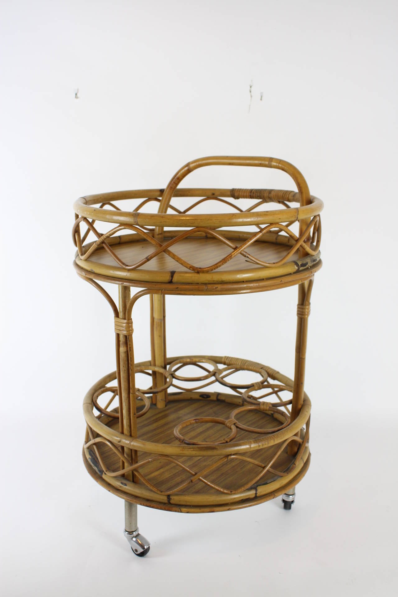 Spanish bar cart in Mediterranean style. It has two shelves; each shelve has a melamine base and the structure of the bar cart is made of bamboo and wicker.
Three steel wheels.