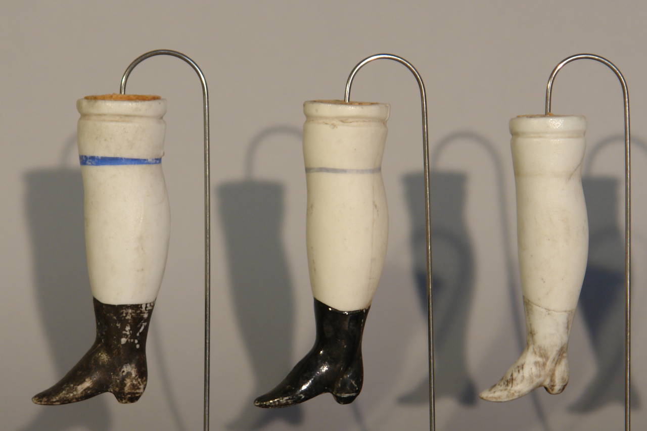 A collection of 19 French Porcelain Doll Legs mounted on 3 stands 3