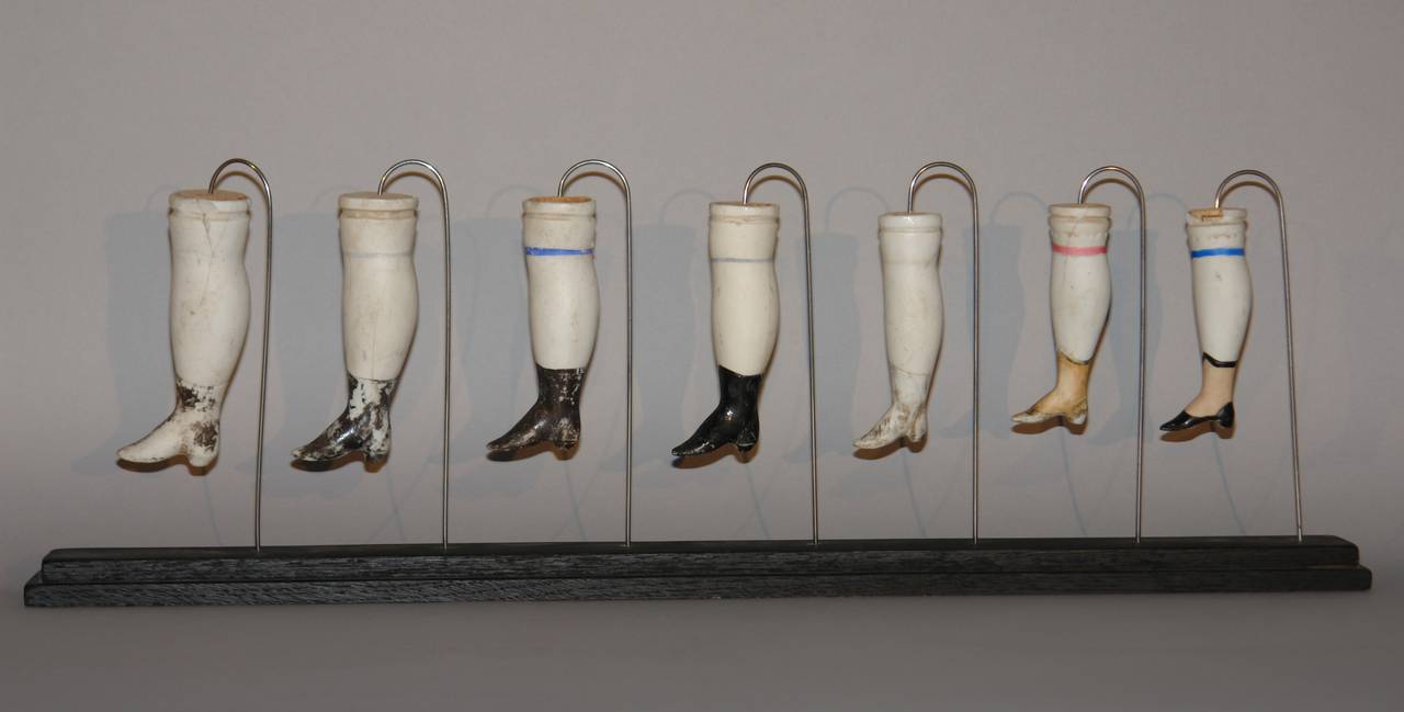 An interesting collection of 19 shapely French porcelain doll legs with heeled boots mounted on 3 wood stands.

legs range from 3