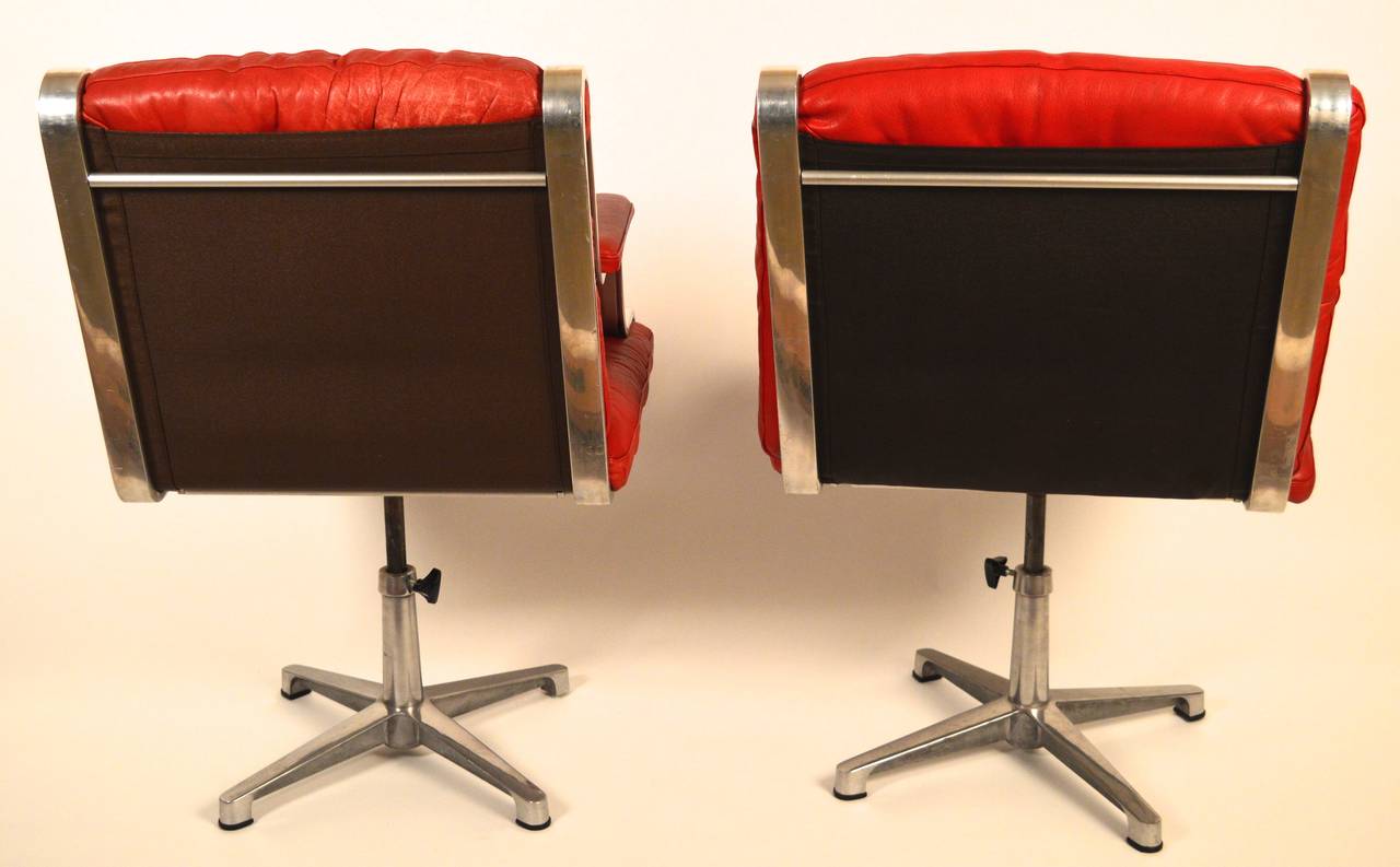 A pair of Circa 1960's lipstick red Swedish  swiveling desk chairs. Both chairs retain the  original red leather upholstery which is in very good condition.The seat height is adjustable from 17