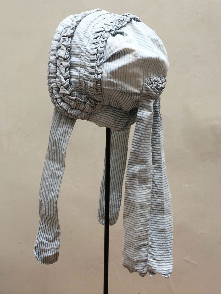 Rare circa 1860 English ladies summer bonnet. The blue and white hand pleated cotton bonnet is displayed on a custom-made metal stand.

The height of 25 inches is including the stand.