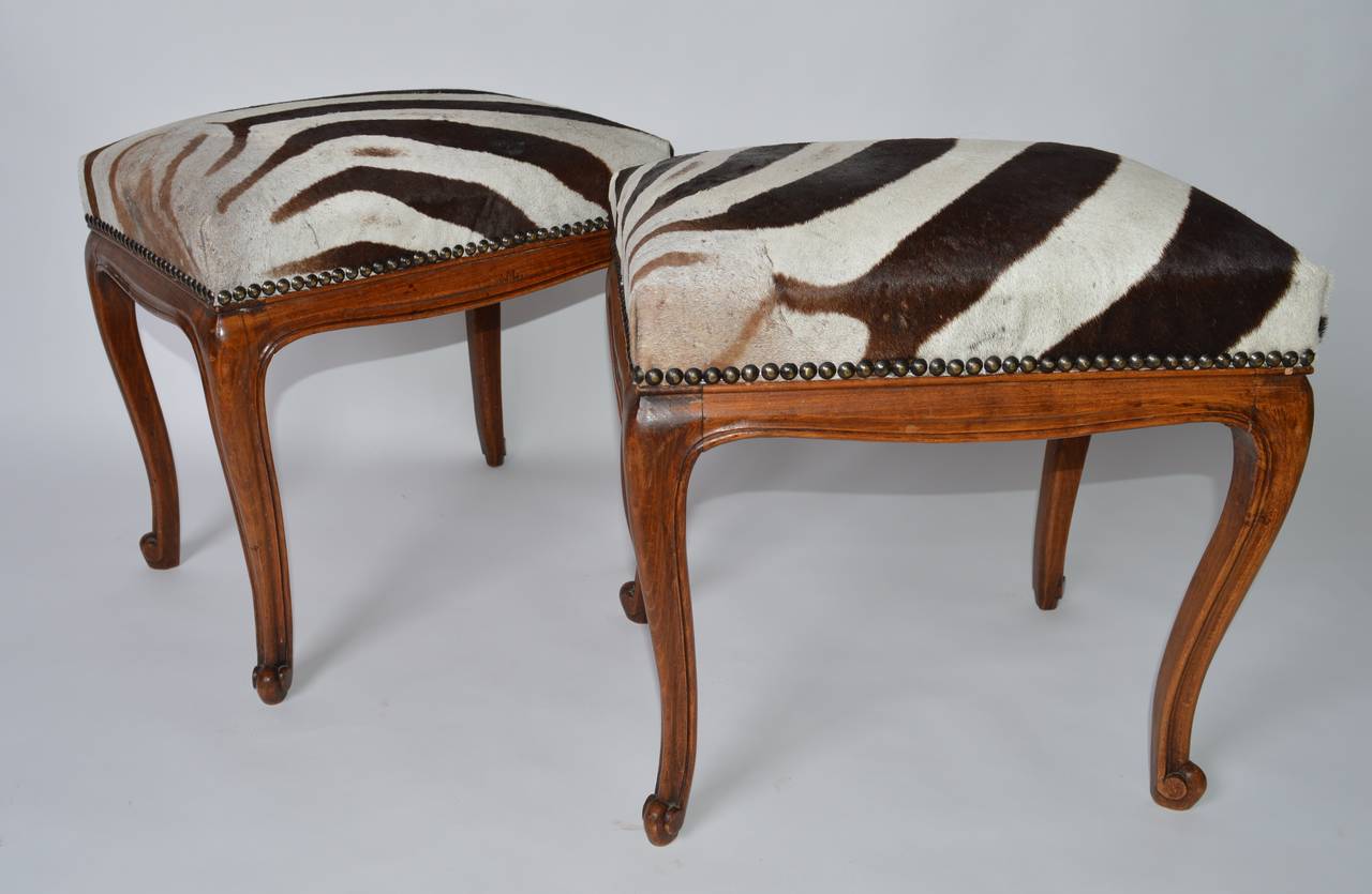 A pair of Circa 1910 French benches constructed in French oak.
The carved cabriole legs ending in escargot scroll feet provide stability
 and support that make these benches appropriate for daily use.
Old zebra skin upholstery and brass nail