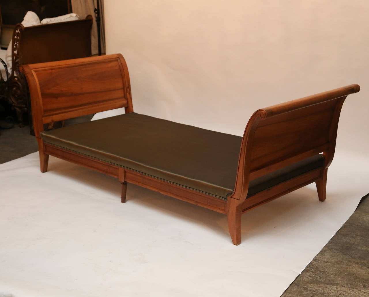 Two walnut sleigh-style daybeds, close to size of twin beds.

Finish is a medium walnut, almost a fruitwood.

Ends are pitched and paneled and legs are splayed.

New mattresses and bolsters are included. 

Remarkable pair, elegant in their