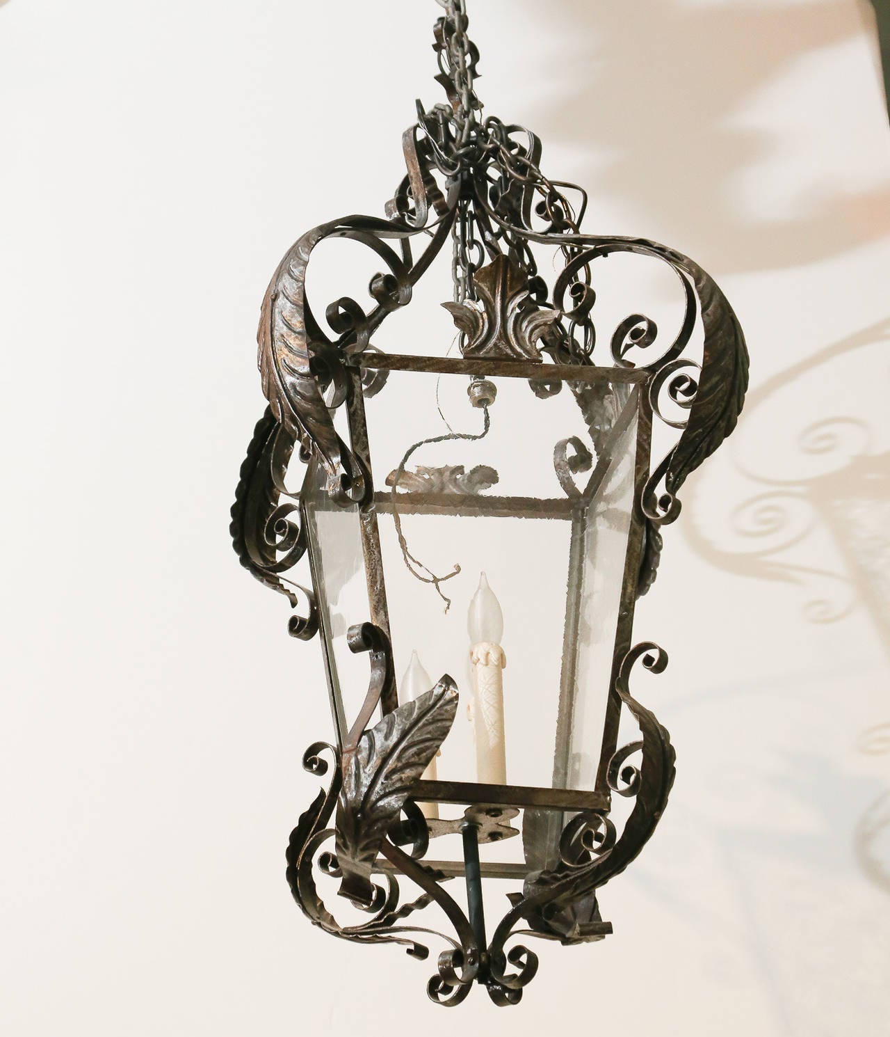 Pair of scrolled wrought iron three-lite lanterns with painted tole acanthus leaves applied.

Has matching ceiling canopies to match