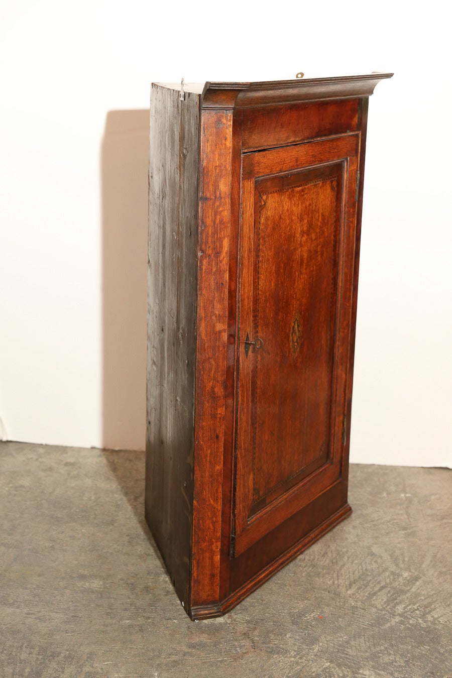 Antique English Oak Corner Cabinet with small inlay in center of door.

Two scalloped edge shelves.