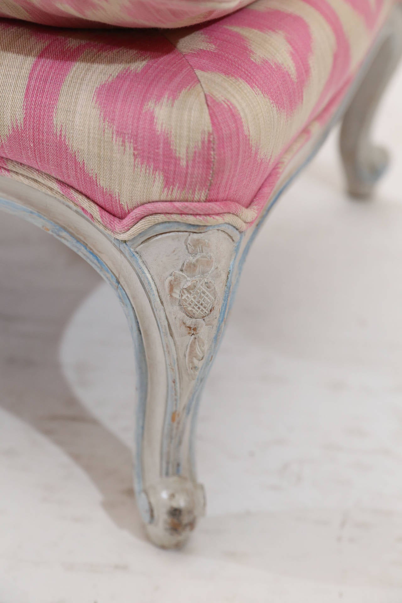Low siting arm-less painted bench with simple frame resting on carved cabriole
legs.

Front apron continues the carved motif of legs.

Upholstered in Hot-Pink Ikat fabric.

Precious piece for foot of a bed.