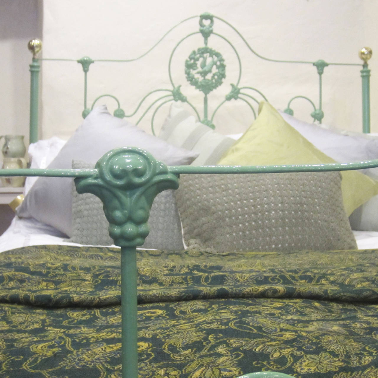 A double cast iron bed with ornate panel decoration featuring a 'bird's nest' and brass knobs. This bed has been powder coated in one of our new colors asparagus, a soft calming green.

The price is for the bedstead alone. The base, mattress,