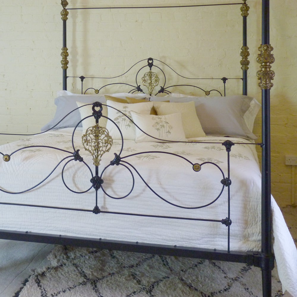 A superb example of a mid-Victorian cast iron four-poster bed bedstead with tapered posts, arched canopy and ornate brass fittings.

We have extended this bed out to 6 ft wide from an original frame, circa 1870, and refinished in black. The brass