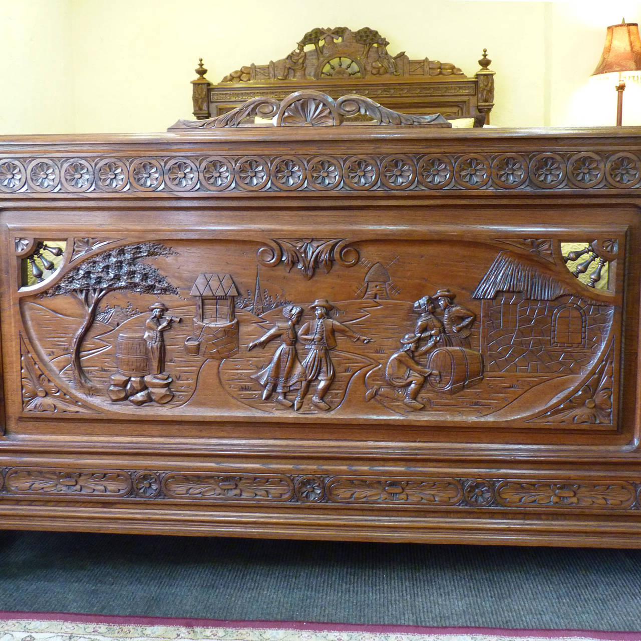 A superb Breton bed from the Brittany region of France in oak, with fine carving. This was probably a marriage piece with husband and wife depicted on the pediment and dancing scenes of merriment on the foot board, possibly showing wedding
