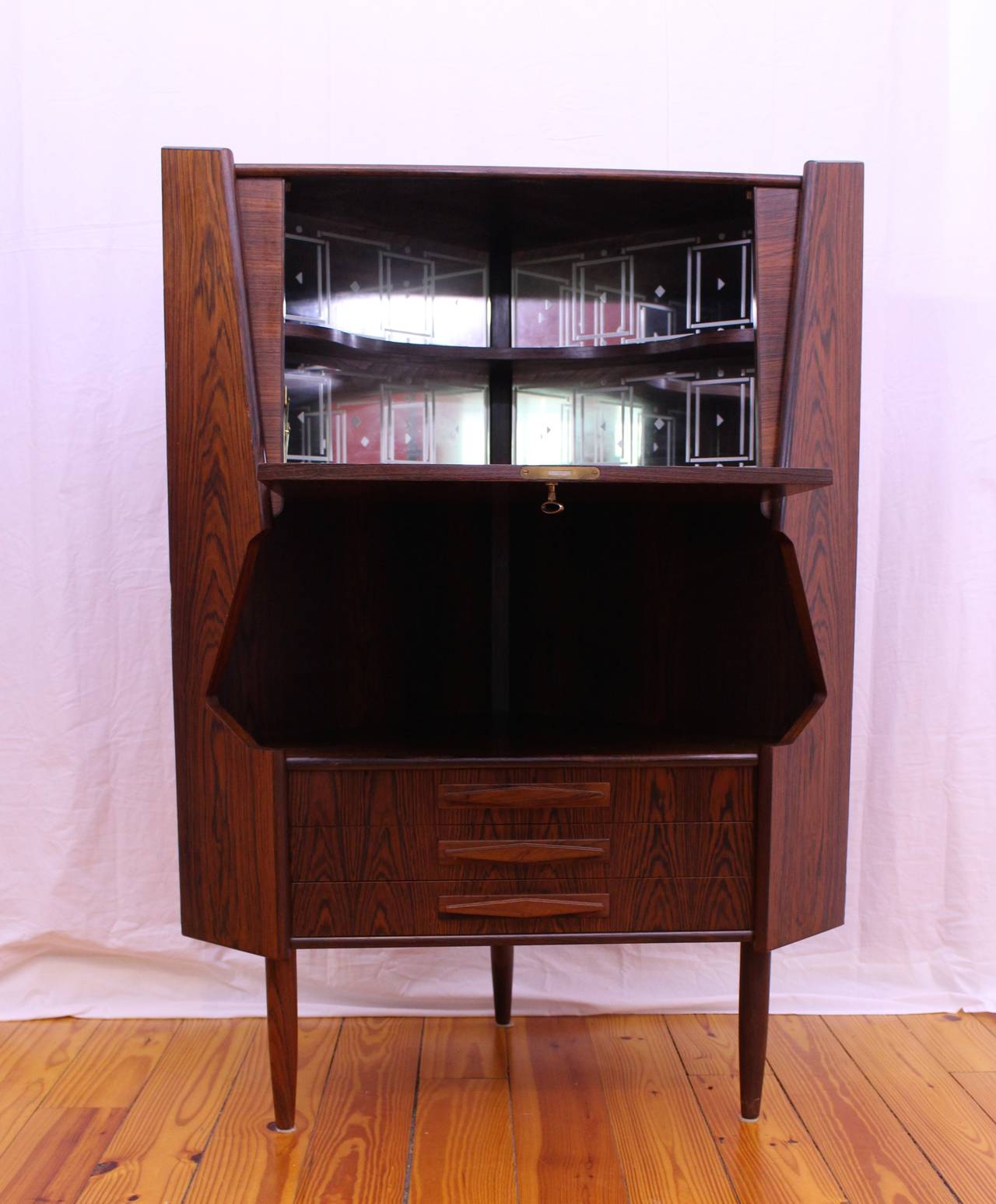 Unique rosewood corner cabinet designed by Johannes Sorth for Nexø Møbelfabrik. The inside is lined with mirrors and would make for a perfect bar, or storage piece for a dining room.