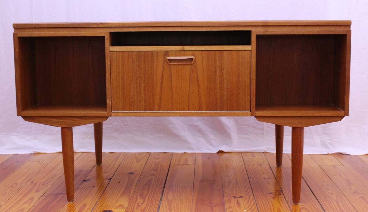 Uniquely beautiful desk made out of teak. This desk features several storage drawers that are easily accessible when you are working to discreetly hide messy papers, pens and other desk items. The other side of this desk features shelves and an pull