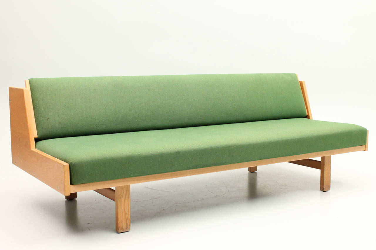 Gorgeous green and teak sofa / daybed by Hans Wegner for Getama. The back of the sofa slides up to turn into a daybed. This item is in excellent condition and recently reupholstered.