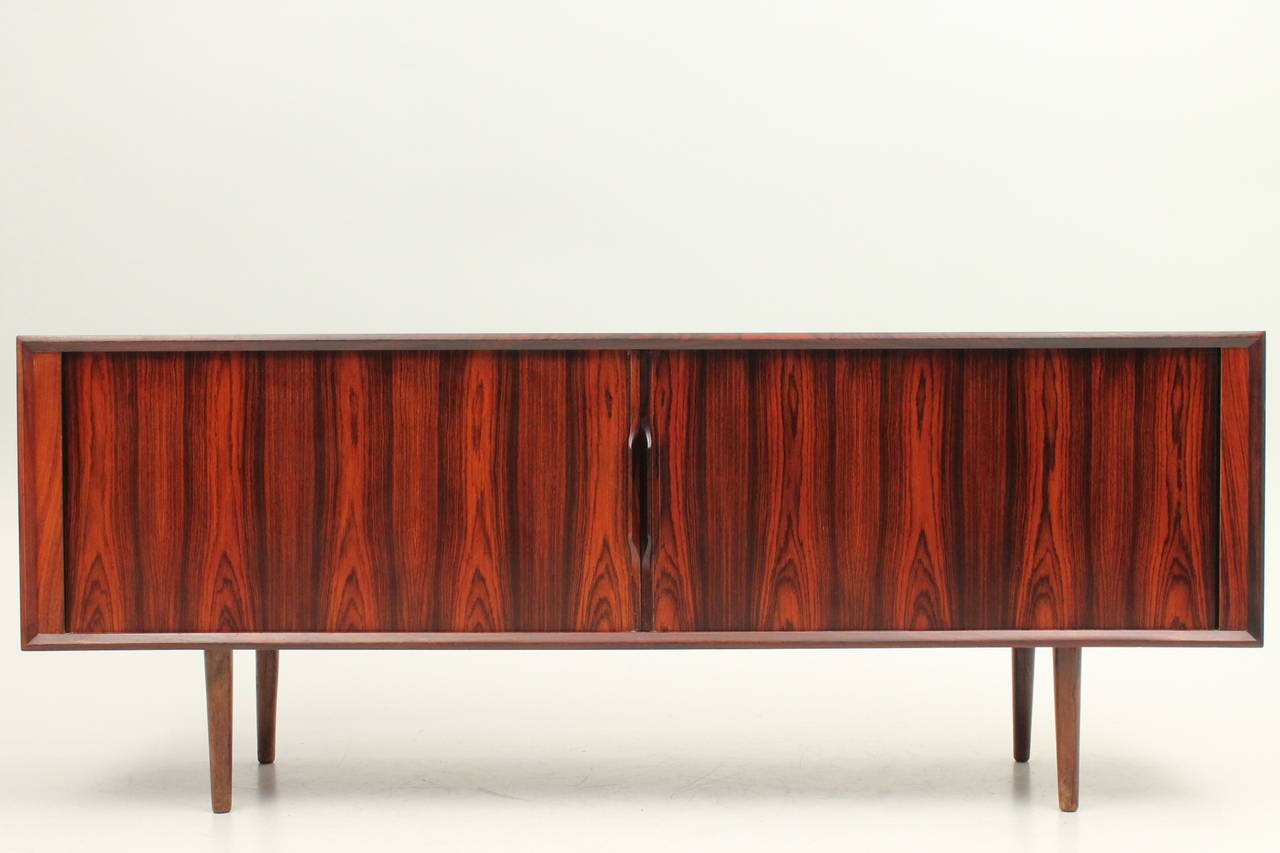 Large rosewood Ib Kofod Larsen credenza with stunning dark grain and roll front. This item is in excellent vintage condition with the original tag in tact!