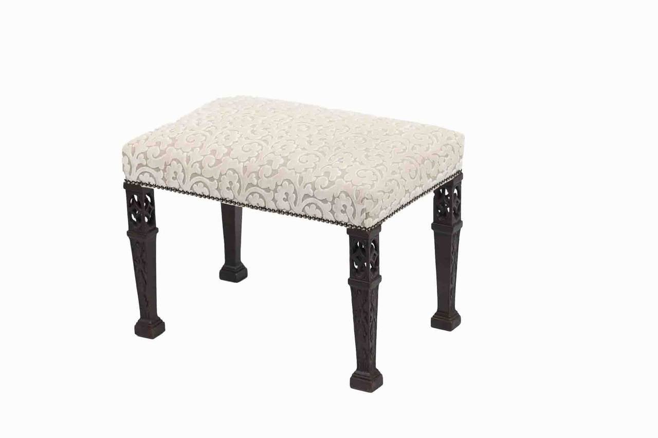 A 19th century Gothic revival style stool, the stuffover seat on open fret and carved tapering legs. Terminating on stepped feet.
