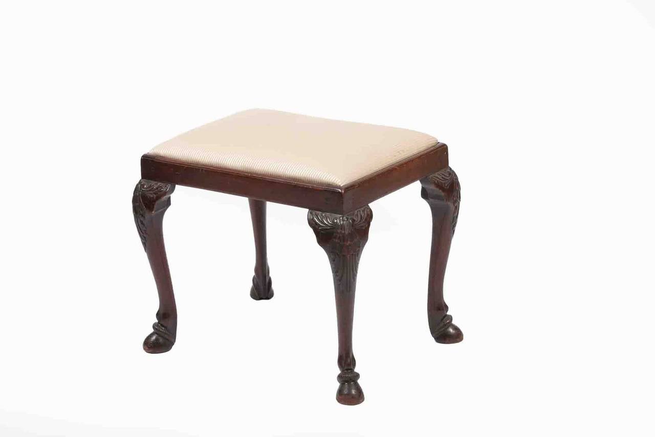 19th century mahogany stool with drop in seat raised on cabriole legs with leaf and shell carving terminating on hoof feet