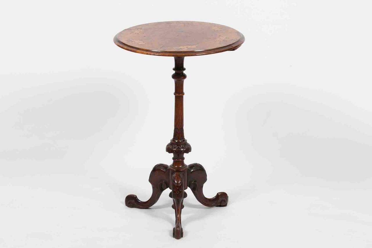 19th century Regency walnut occasional table, moulded circular top inlaid with donkey's and riders raised on a ring turned pod, carved with stylised leaves on tripod scroll carved legs with elegant scroll feet.