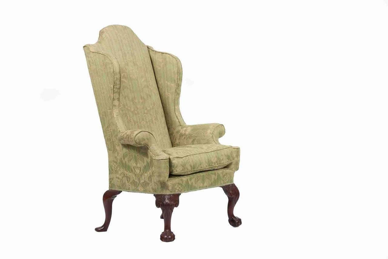 A 18th Century Wing back chair with tall peaked backed
and out swing scrolling arms with a square seat raised on cabriole
legs with acanthus carving terminating with ball feet.